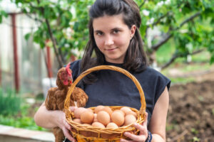 How Animal Husbandry Enhances Homesteading Woman Holding Chicken and Basket of Eggs