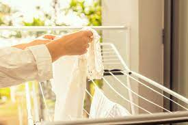 Key Features to Look for in an Indoor Drying Rack Woman Hanging Clothes on Rack Near Window