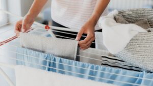 Tips for Using an Indoor Drying Rack Woman hanging clothes on rack with basket
